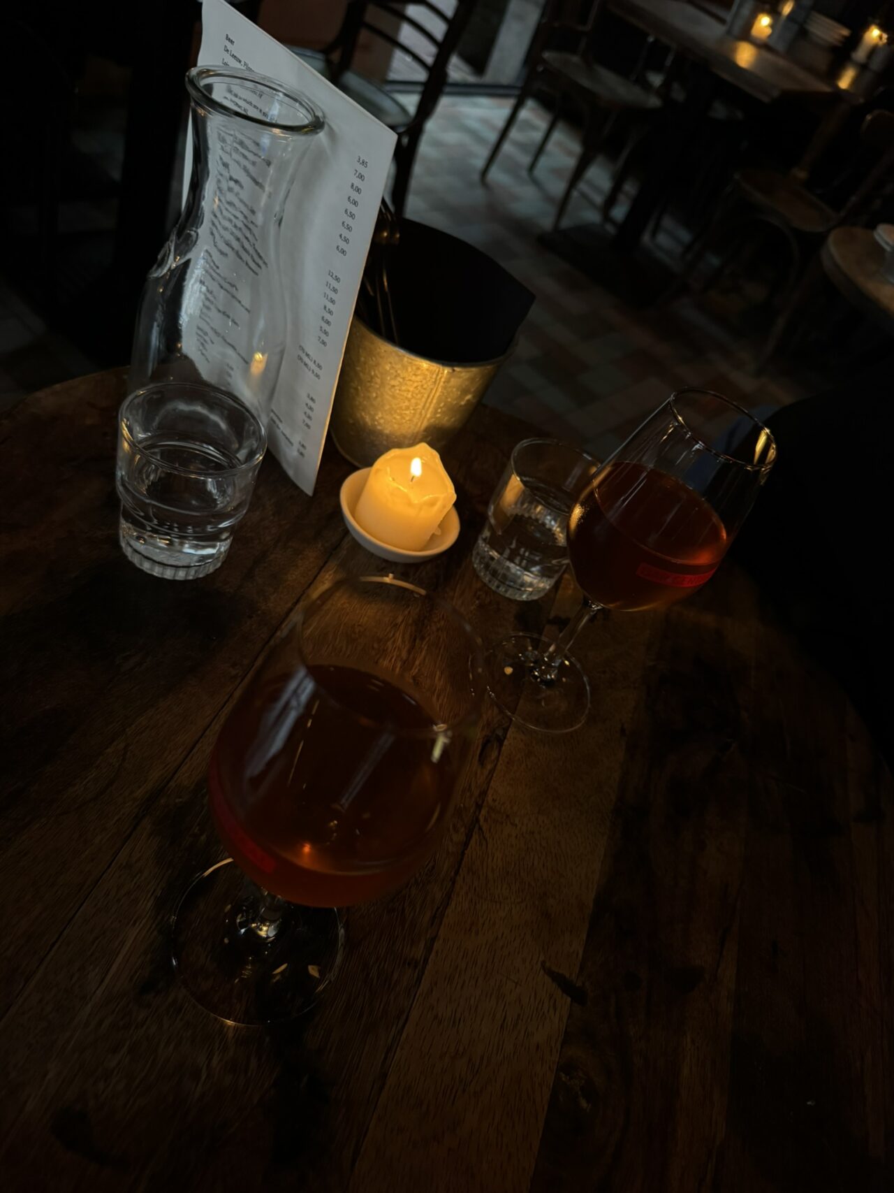 Copas de vino y una vela sobre una mesa de Bar Centraal.