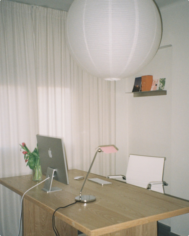 Mesa de estudio con ordenador, tulipanes y lámpara de papel.