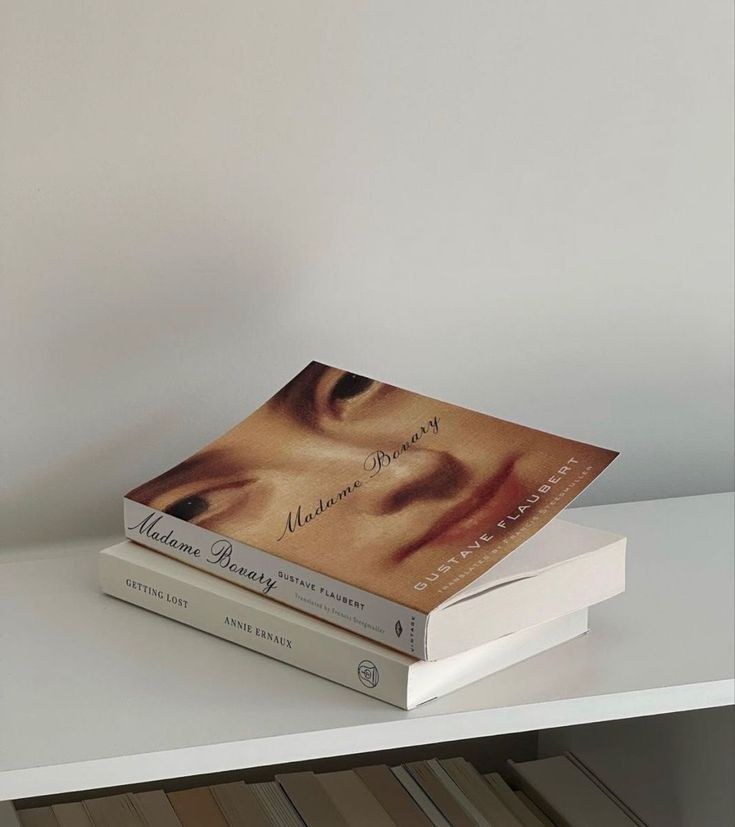 Pila de libros sobre una balda blanca.