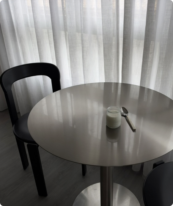 Mesa circular con una taza delante de una ventana.