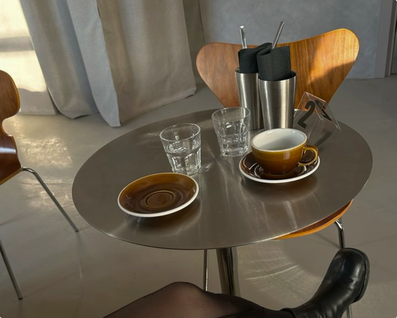 Mesa de cafetería con tazas de café y sillas de madera.