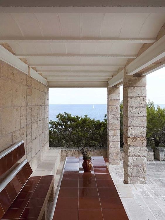 Terraza de Can Lis, con bancos de piedra y vistas al mar entre columnas.