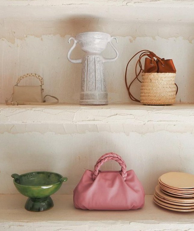 Detalle de los estantes de piedra de Datura Estudio Isla, con bolsos, cerámica y vajillas.