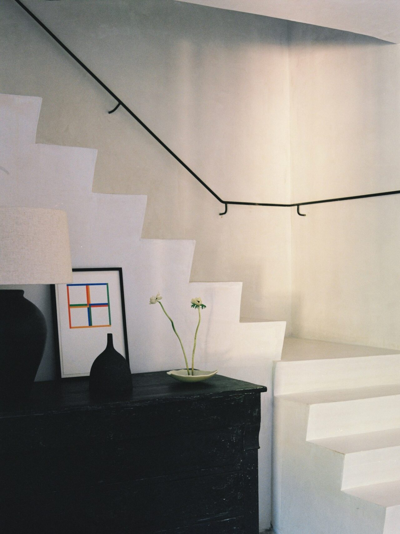 Escalera blanca y mueble oscuro en un interior de Studio AR.DE. Fotografía de Hugo de Pablo.