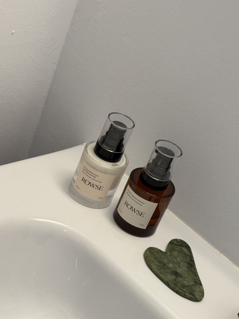 Dos productos de cuidado facial y una piedra gua sha junto al lavabo.