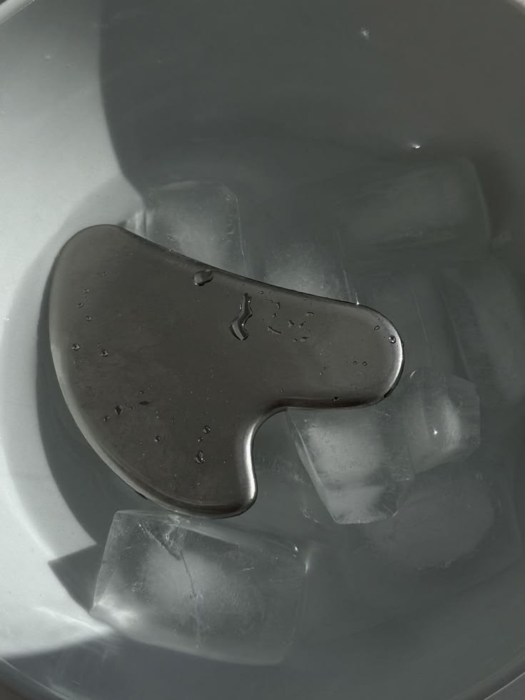 Piedra gua sha sobre una superficie húmeda.