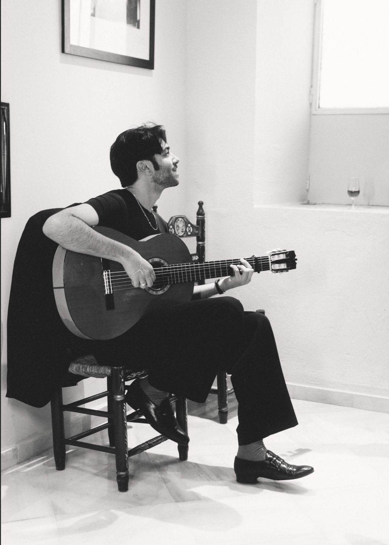 Yerai Cortés sentado, tocando la guitarra, en una fotografía en blanco y negro.