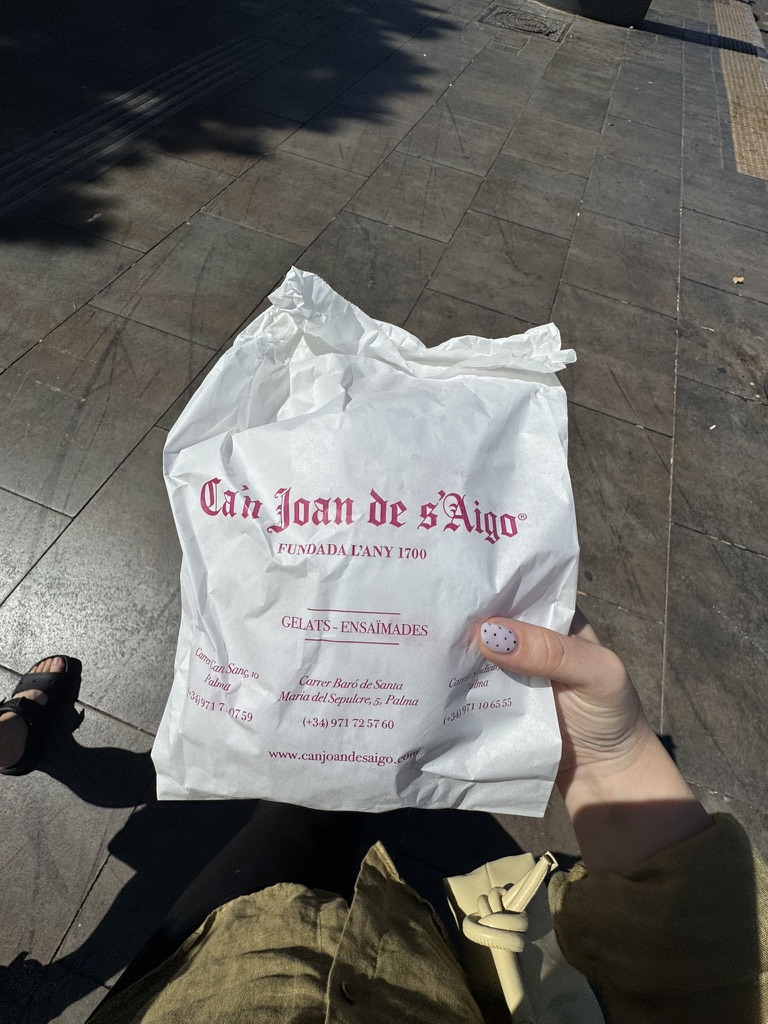 Una bolsa de Can Joan de s’Aigo sostenida sobre una acera.