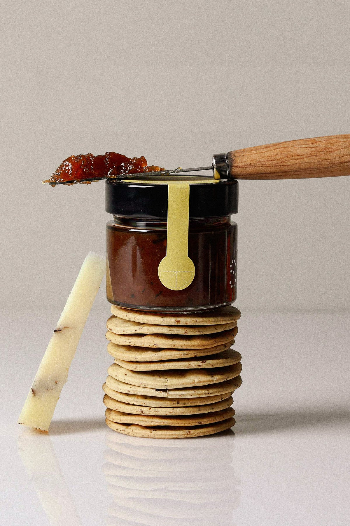 Tarro de mermelada de Sonmo sobre galletas, con cuchillo y queso.