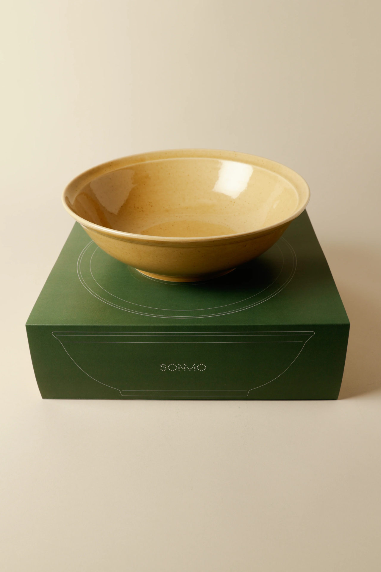 Cuenco amarillo sobre una caja verde de Sonmo.